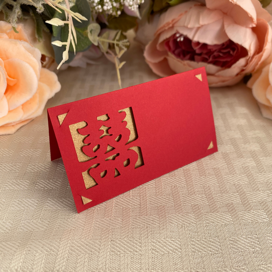 Red folded place card with a gold backing meant for Chinese weddings with double happiness sign