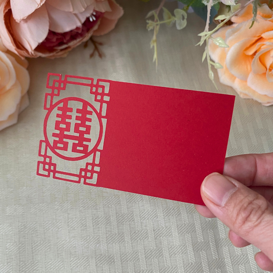 Red cardboard place card with the double happiness symbol carefully cut into a Chinese pattern